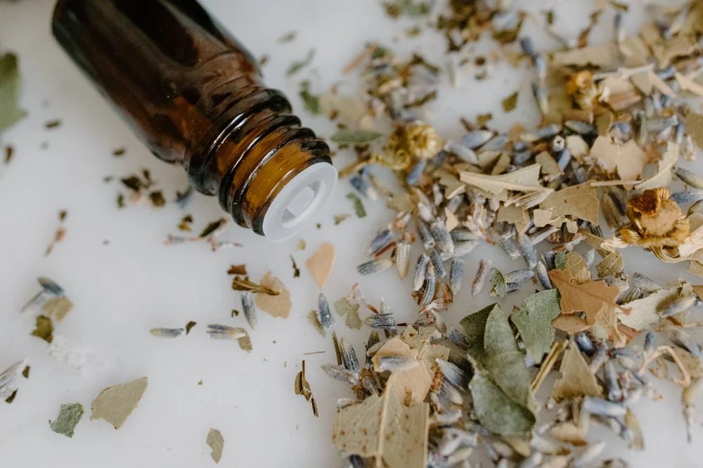 Flacon d’huile essentielle renversé, entouré de plantes séchées