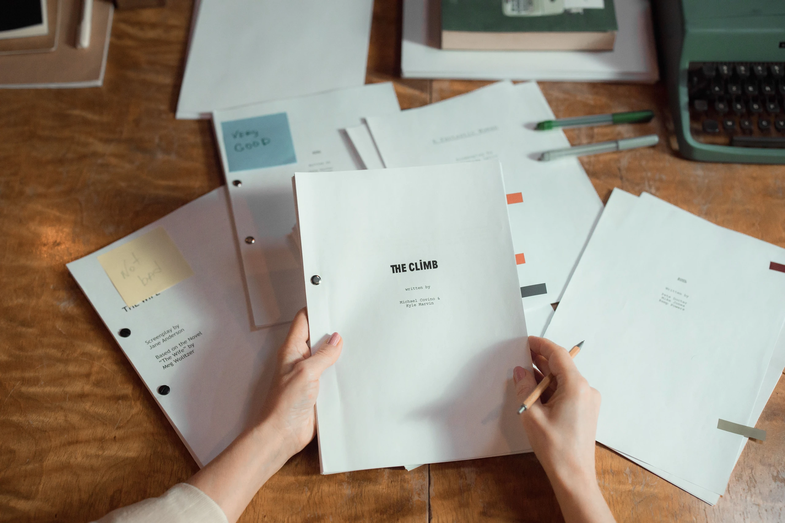 Mains tenant un manuscrit sur un bureau couvert de feuilles