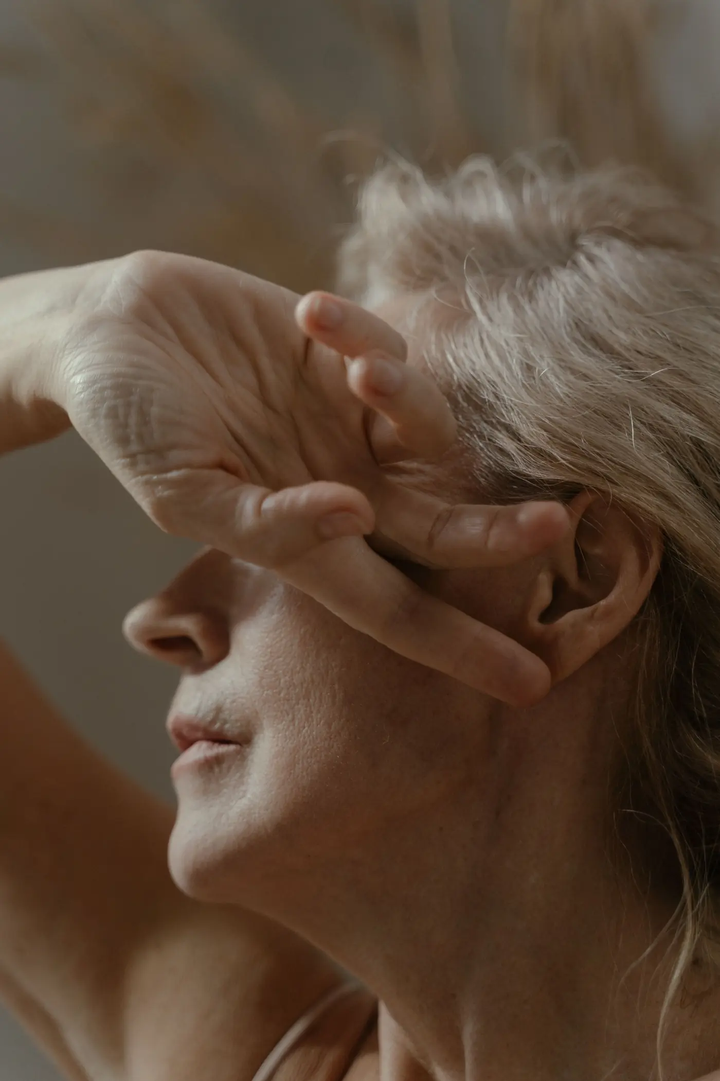 Femme aux cheveux argentés, la main près du visage