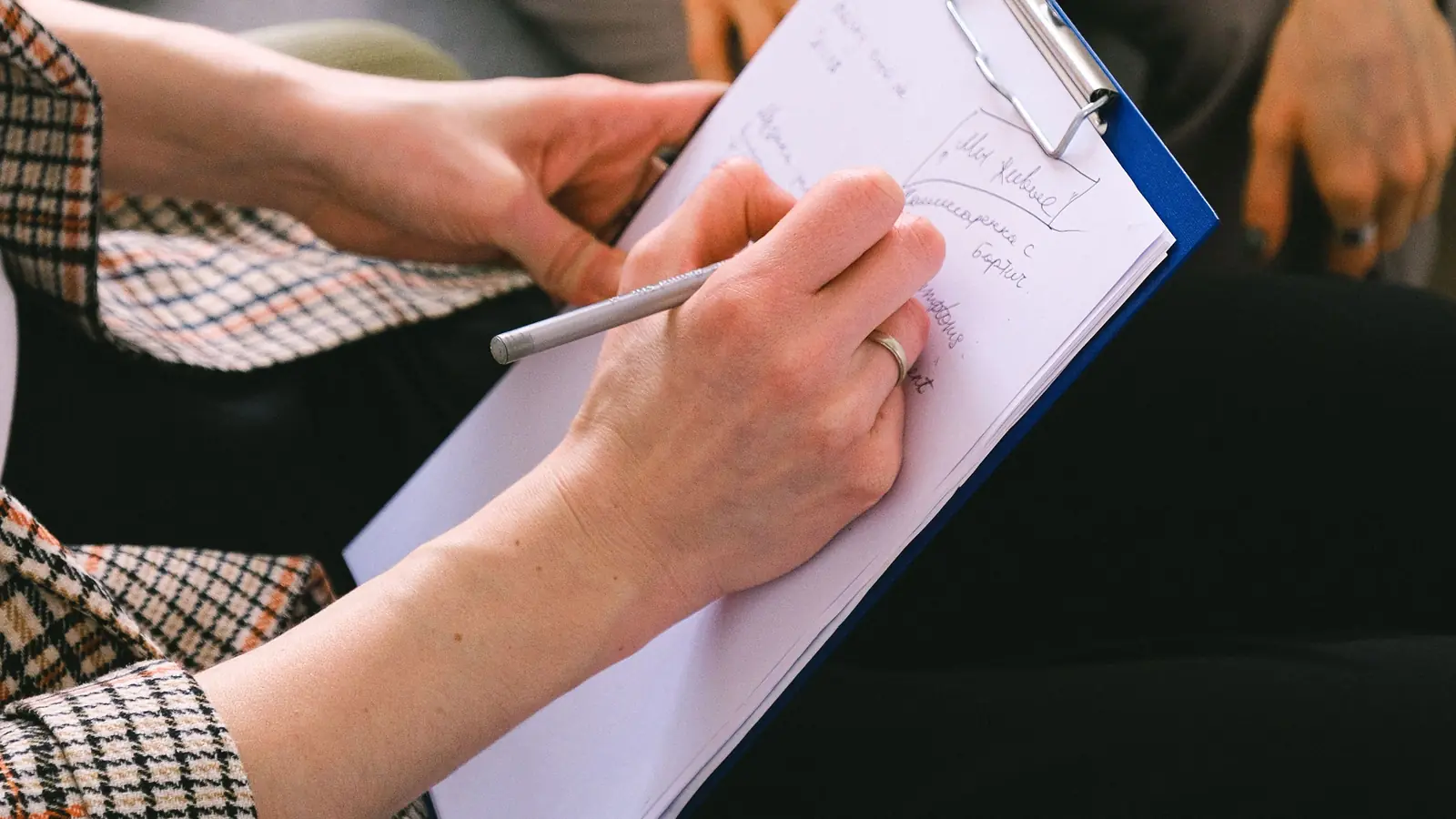 Mains prenant des notes sur un porte-bloc lors d’une consultation